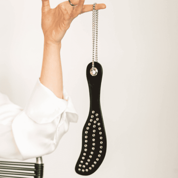 Photo of a woman wearing the black leather studded paddle.