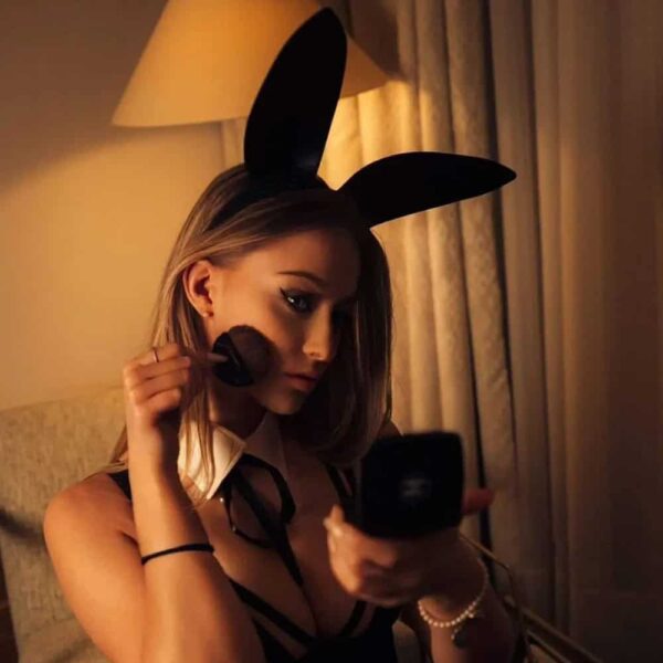 woman wearing black rabbit sensual roleplay lingerie costume woman wearing black rabbit sensual roleplay lingerie costume that applies blush while looking into a pocket mirror