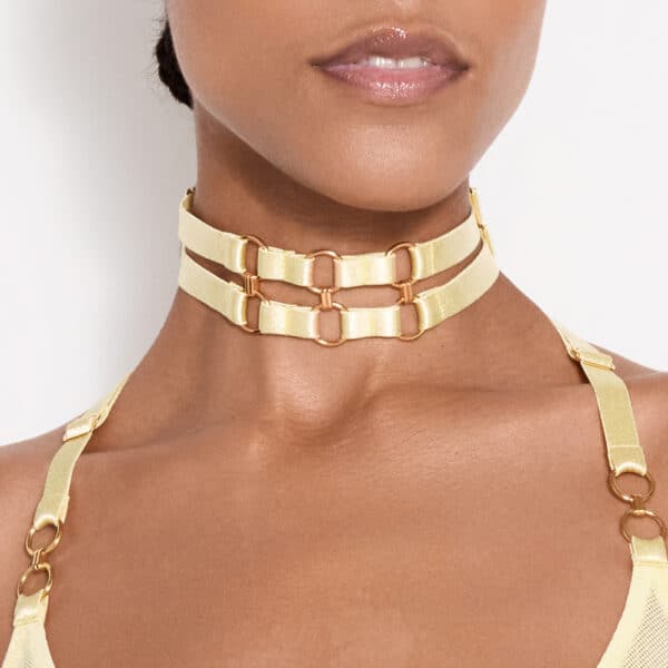 a dark-skinned woman wears a yellow two-strap necklace that connects to a gold circle