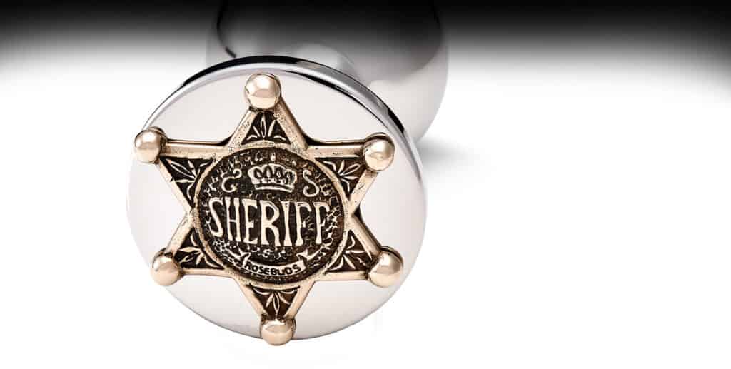Accesorio plug anal de bronce plateado con decoración de estrella de sheriff dorada.