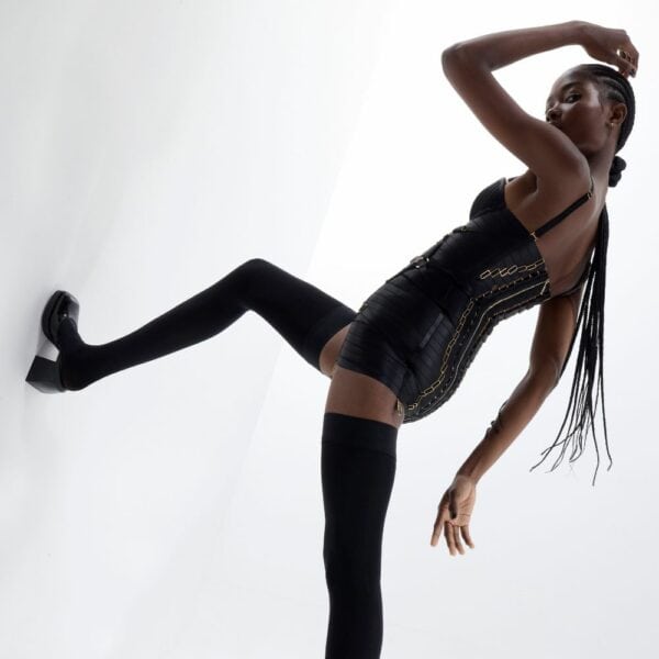 Woman wearing black Angela Bondage dress on white background.