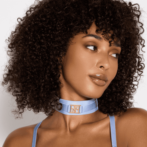 Mujer con collar elástico azul cielo con logotipo dorado