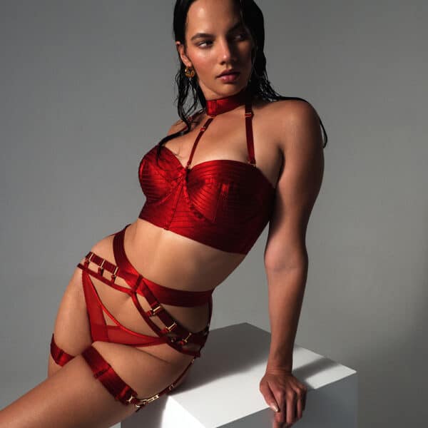 Woman wearing a red lingerie set with gold details.