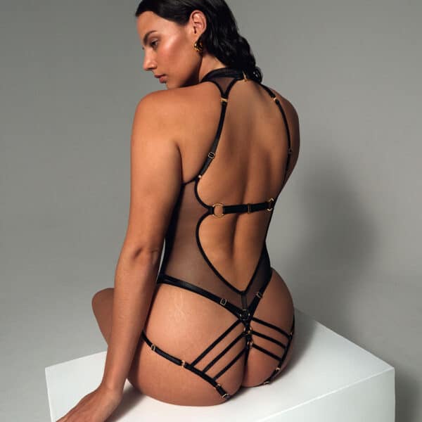La mujer lleva un body negro transparente con tirantes ajustables y espalda abierta.