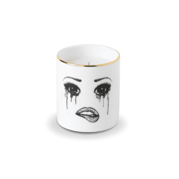 A scented candle in white Chinese porcelain features a melancholy face, carefully traced in felt. The face expresses sadness with flowing tears and melting make-up, while the lower lip is delicately bitten, creating a moving and artistic composition.