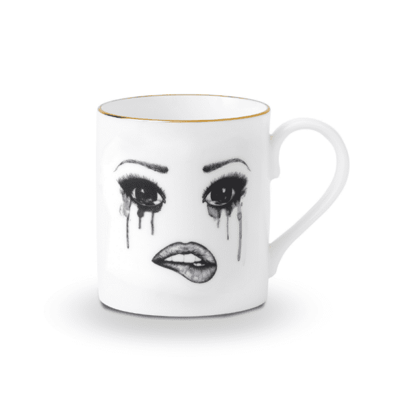 Una taza de porcelana china blanca presenta un rostro melancólico, cuidadosamente trazado en fieltro. Este rostro expresa la tristeza con lágrimas que fluyen y maquillaje que se derrite, mientras que el labio inferior está delicadamente mordido, creando una composición conmovedora y artística.