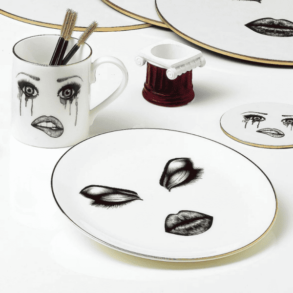 Una colección de vajillas adornadas con caras personalizadas y cautivadoras expresiones faciales cobra vida sobre una mesa blanca.