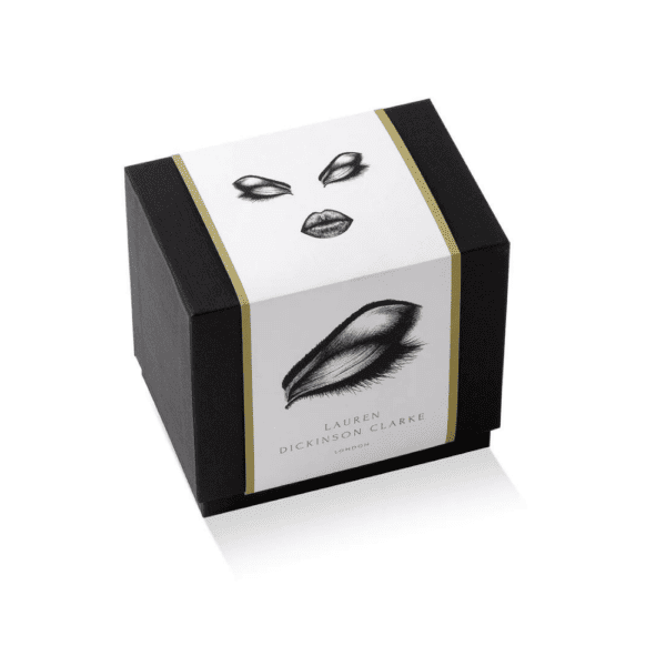 El envase, especialmente diseñado para las velas prima donna, es de color negro y presenta ilustraciones de ojos, complementadas con un elegante acabado dorado.