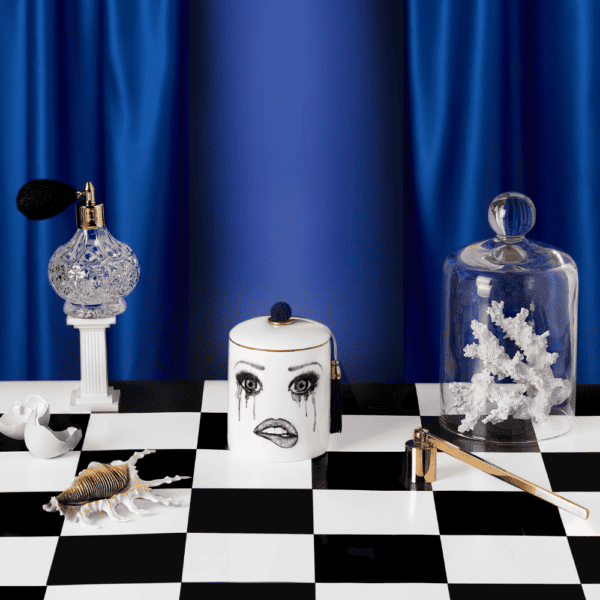 Triste bougie poète parfumé posé sur un damer décoré d’objects en cristal, de corail, coquille d’oeuf et or