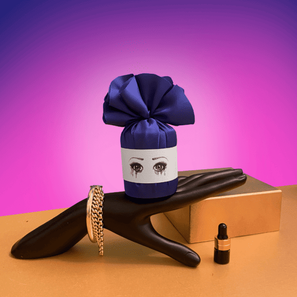Triste poète bougie parfumé emballé en violet posé sur une main noire décoré d’or