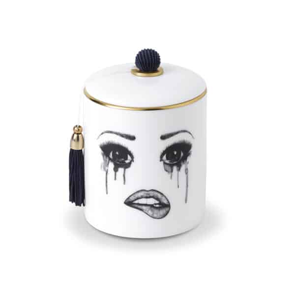 Une bougie parfumée en porcelaine chinoise blanche arbore un visage mélancolique, soigneusement tracé en feutrine. Ce visage exprime la tristesse avec des larmes coulant et un maquillage qui se fond, tandis que la lèvre inférieure est délicatement mordue, créant une composition émouvante et artistique.