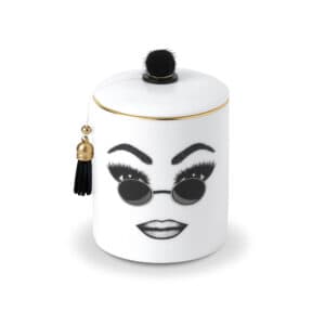 A white Chinese porcelain scented candle features a confident face, carefully traced in felt. This face expresses self-confidence, comfort and cool with round sunglasses and perfectly executed make-up.