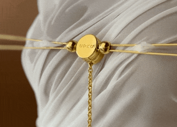 Zoom video of a golden accessory placed on the chest of a woman dressed in white.