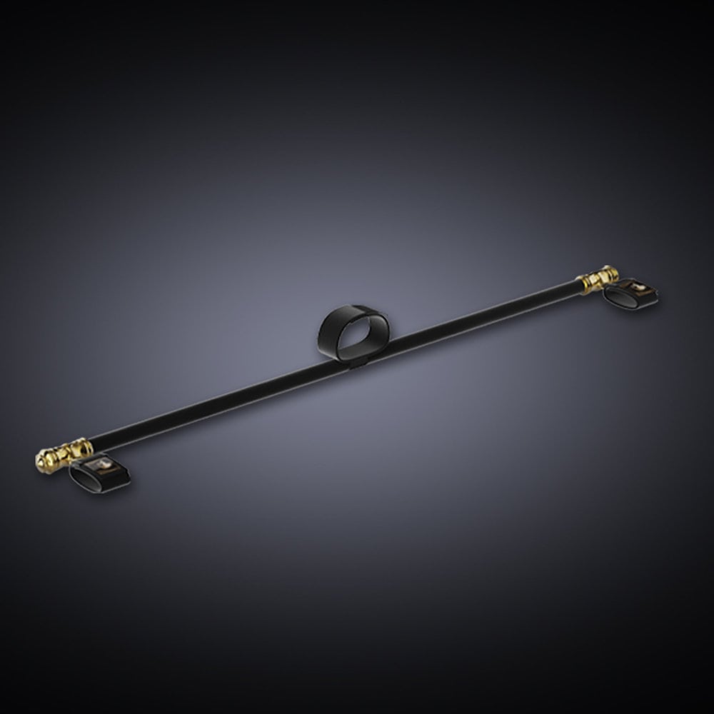 Black background photograph showing a black spreader bar with a collar in the middle and two gold ends with hand ties.