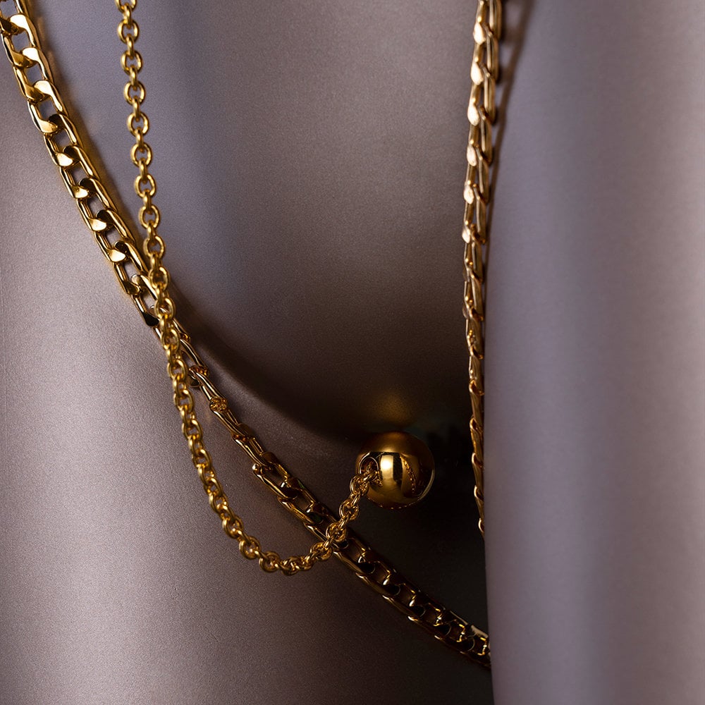Photographie sur mannequin d'une chaine clitoridienne avec un boule de plaisir, les chaines sont dorées.
