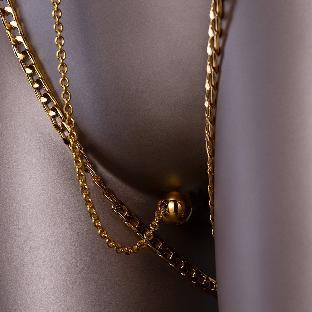 Mannequin photograph of a clitoral chain with a pleasure ball, the chains are gold-plated.