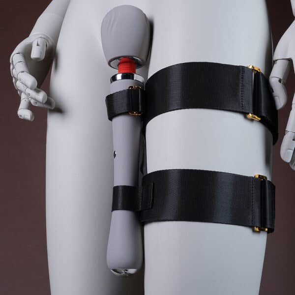 Image showing a leg to which a set with a black harness and a white vibrator is attached.