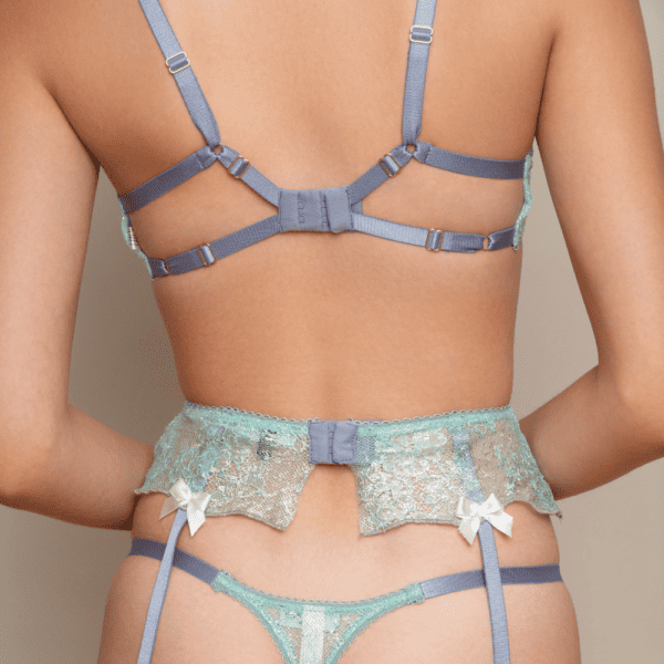 Photographs of a standing woman wearing the Fedra set. The set comprises a bra, thong and light-blue garter belt.