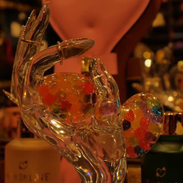 Showroom zeigt eine Handpuppe aus Glas, die einen Funfetti Crystal Delights Plug hält und Nagelringe Brigade Mondaine Signature trägt.