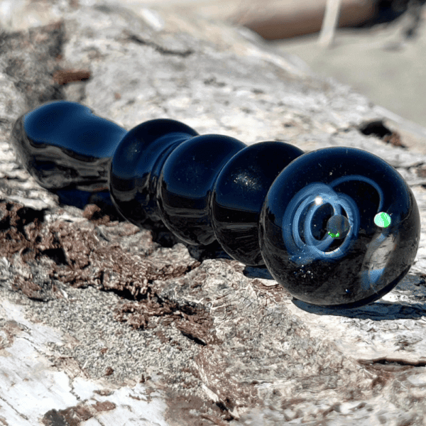 Photograph of dildo galaxy black on white background, midnight blue with constellations and levitating green planet