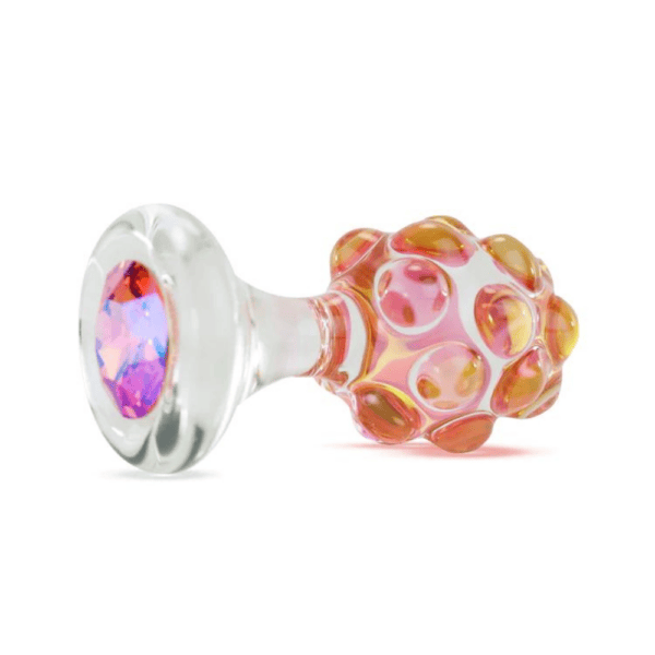 Photographie packshot sur fond blanc d’un plug transparent et texturé représentant un ananas avec des tonds roses et un diamant violet au dos.