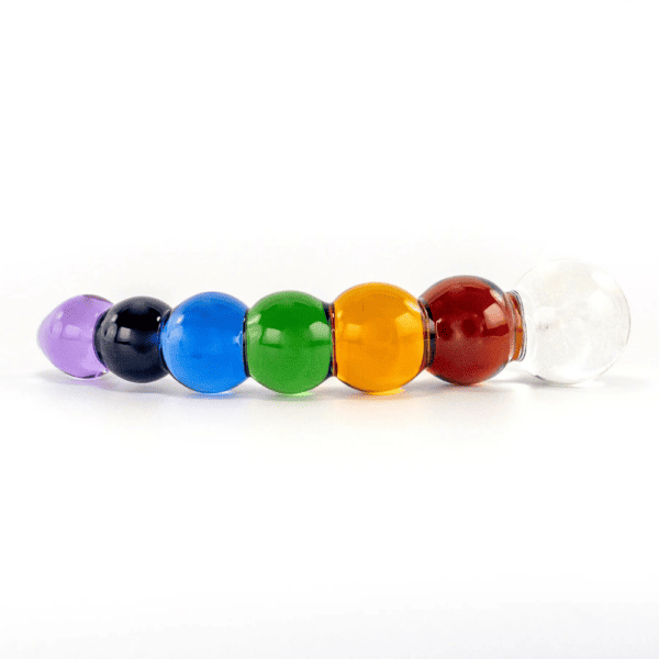 Photograph of a dildo on a white background, it represents a rainbow, it is colored with white, red, yellow, green, blue, navy, purple, a festival of confetti and colors.