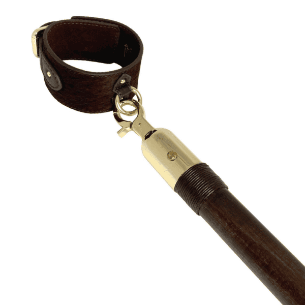 White background photograph of the Spreader Bar with gold details hanging from a handcuff