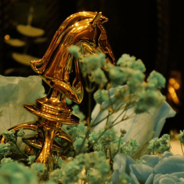 Fotografía de un caballo dorado de un juego de ajedrez de juguete sexual en un ramo de flores azules