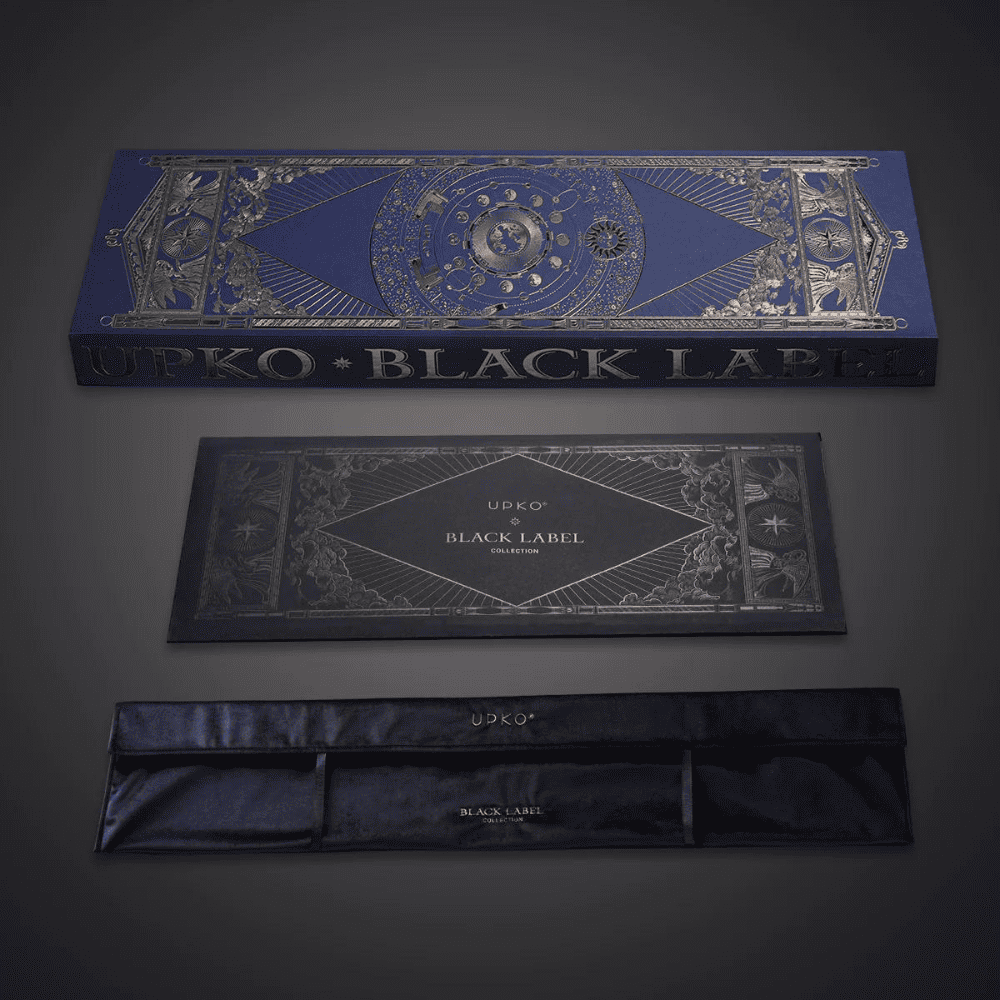 Fotografía de fondo gris del embalaje azul y dorado, caja con bolsa de terciopelo con la inscripción "UPKO BLACK LABEL COLLECTION".