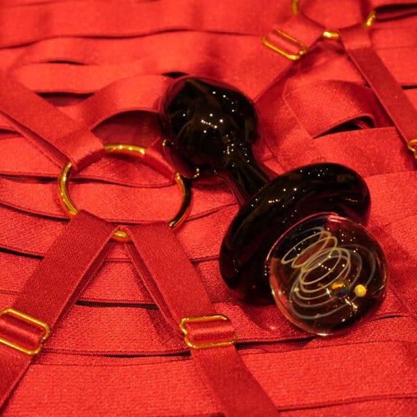 Sala de exposición que muestra un plug Galaxy Crystal Delights y un vestido rojo Angela Bondage Bordelle.