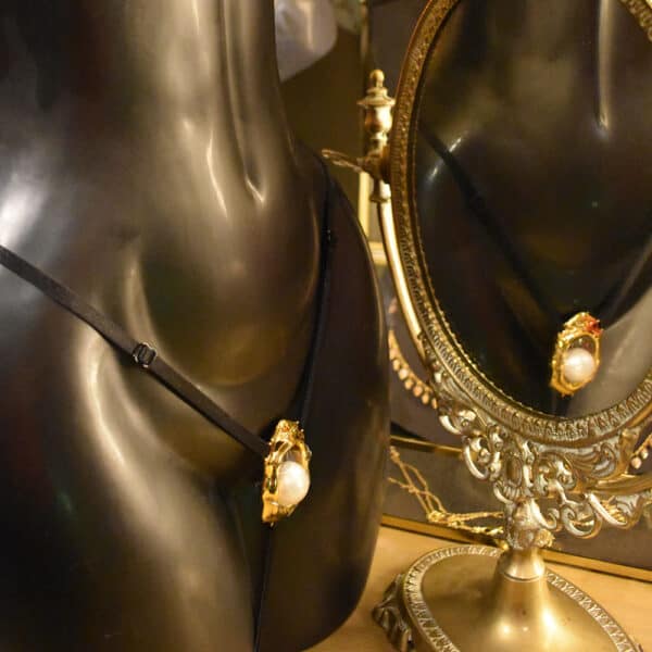 G-String Klitorisschmuck von UPKO an einer Schaufensterpuppe im Showroom, mit einem Spiegel.