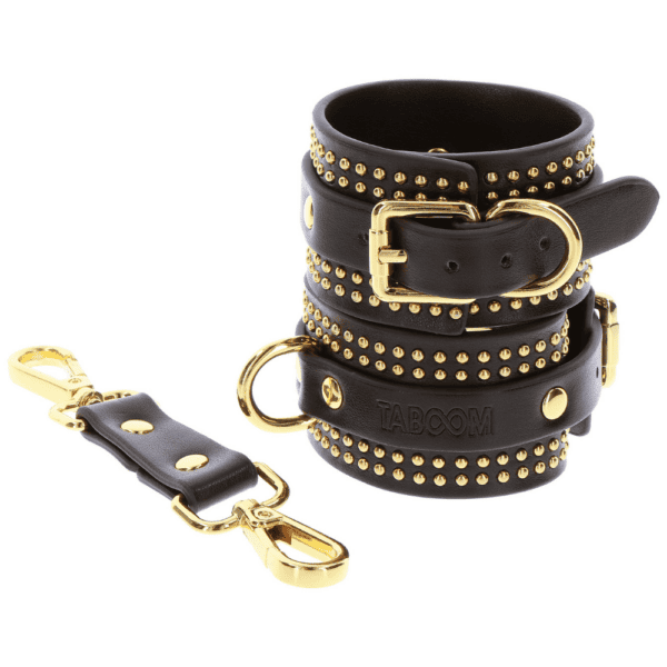 Photo of black leather handcuffs with gold details.