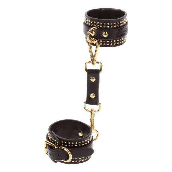 Black leather handcuffs with gold details.