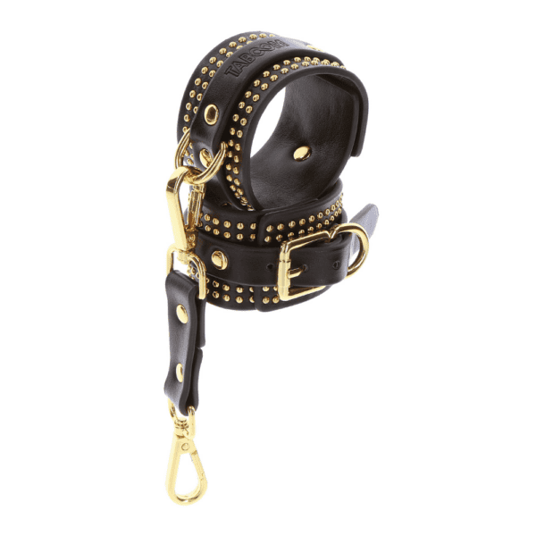 Black leather handcuffs with gold details.