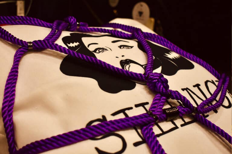 Figura de Una cuerda púrpura de shibari alrededor de un cojín de exposición.