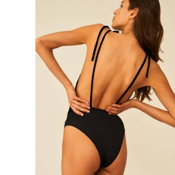 Back model wearing Undress Code once in a blue moon bodysuit, hands on hips against a light background.