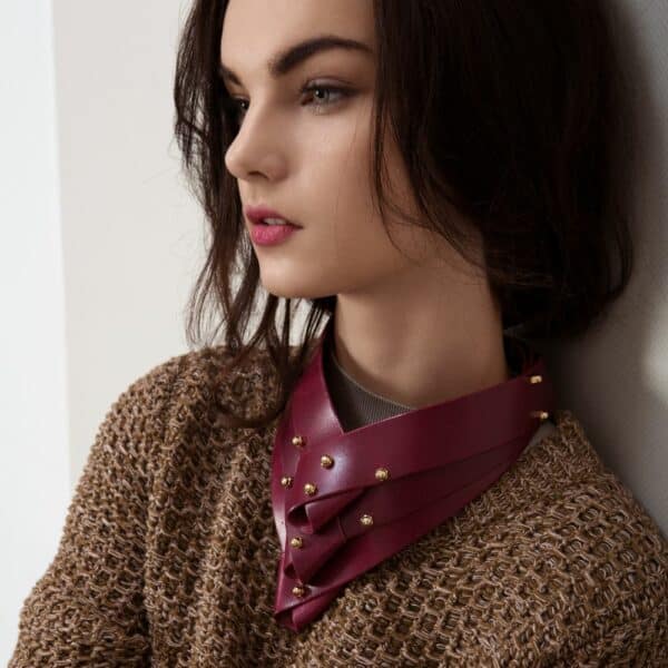 Photograph of Una Burke's Turned necklace in burgundy leather worn by a woman over a sweater.