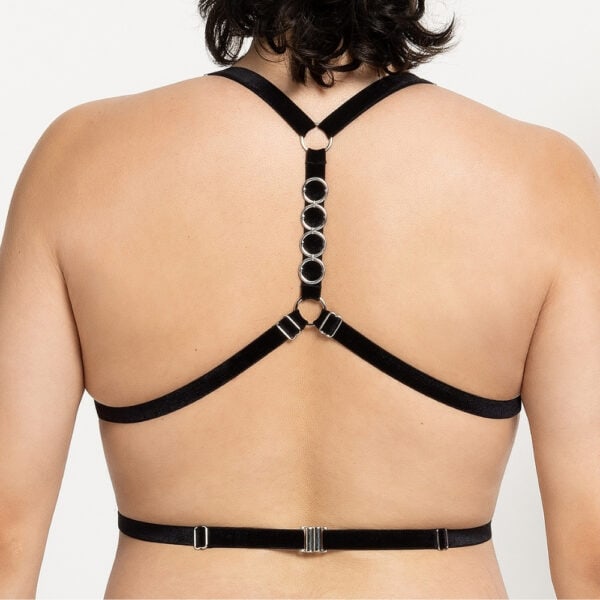 Mujer de espaldas que lleva un arnés de terciopelo negro con hebillas de cadena de plata
