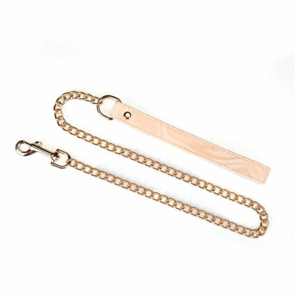 Pink Boudoir Amor bondage necklace in pink and black vegan imitation leather. Gold-plated finish, three D-rings for fastening. With gold chain leash, elegant and adjustable for refined domination.