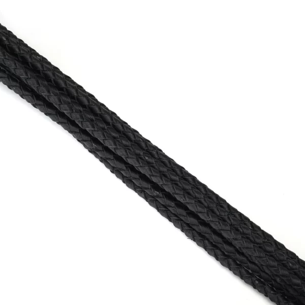 Fouet à neuf queues en cuir noir tressé avec pointes de cuir. Accessoire BDSM léger et maniable, avec prise ferme et boucle de suspension discrète.
