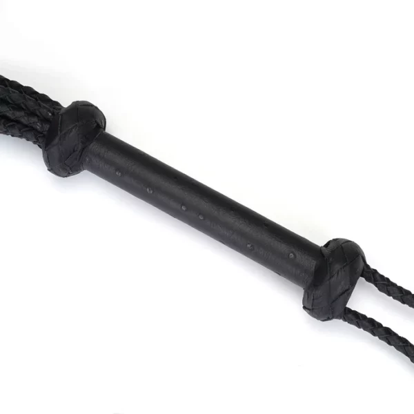 Fouet à neuf queues en cuir noir tressé avec pointes de cuir. Accessoire BDSM léger et maniable, avec prise ferme et boucle de suspension discrète.