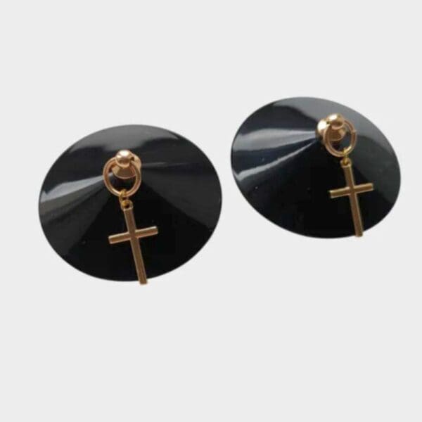 Nippies noirs avec croix dorée signés Yokko Chérie, faits main en France. Accessoire de mode sophistiqué, conçu pour sublimer les tenues audacieuses. Mélange de glamour, sensualité et artisanat.