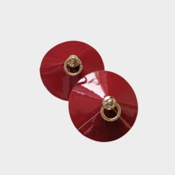 Cache-tétons rouges NIPPIES RED de Yokko Chérie, fabriqués en similicuir souple avec une chaîne dorée, présentés sur un fond élégant. Accessoire sensuel livré avec un pochon en velours et bandes adhésives hypoallergéniques.