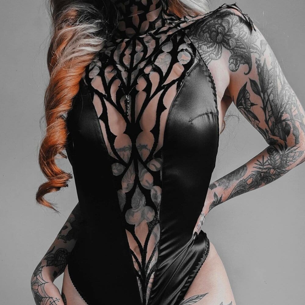 Body gothique brodé en tulle nude, col montant et décolleté en V effet illusion. Détails en satin vegan noir et dos nu. Pièce phare de la collection DOGMA par Videnoir.
