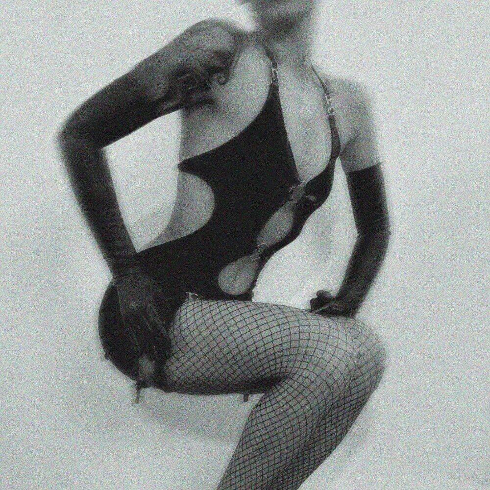 Kalypso-Body aus weichem, dehnbarem Jersey mit klaren Ausschnitten, schwarzen Samt-Akzenten, Metallringen und verstellbaren Trägern für einen sinnlichen und grafischen Stil.