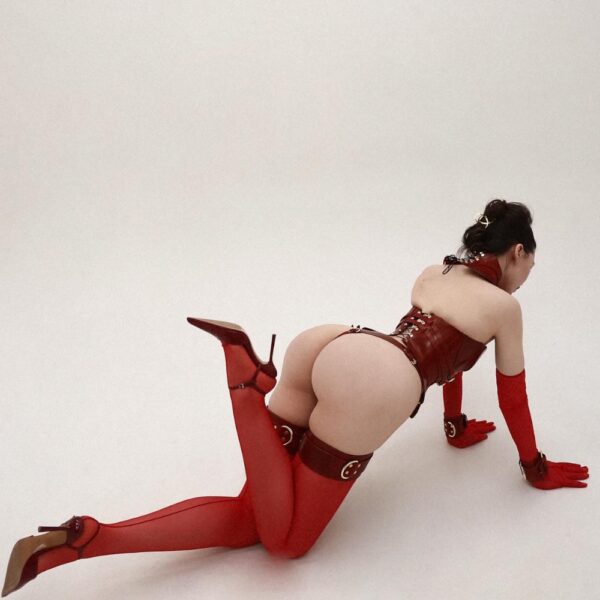 Daelos Korsett, Astrea String, Magnus Oberschenkelzwang und Handschellen aus rotem, vollnarbigem Leder mit Metallbeschlägen, handgefertigte RE:STRICT Bondage-Kreationen.
