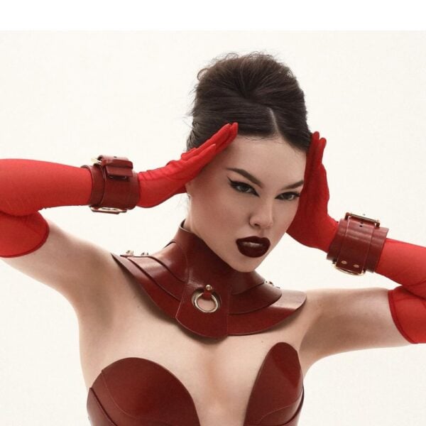 Rote Lederhandfesseln mit goldenem D-Ring und rotem Lederkorsett mit Metallbeschlägen, handgefertigte Bondage-Kreationen von RE:STRICT